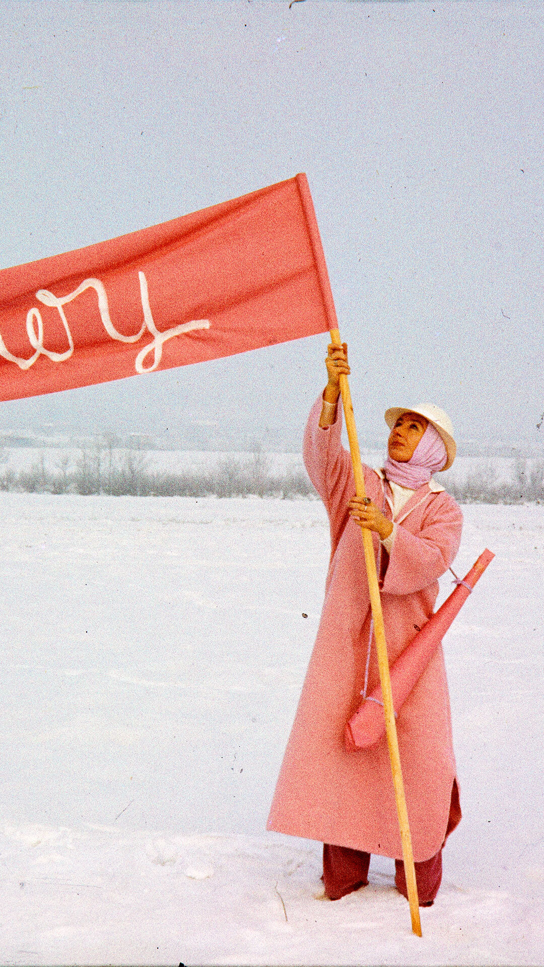 Person in rosa Mantel hält rosa Fahne im Schnee